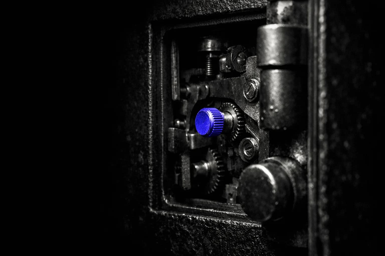 A close-up of a heavy industrial safe with its door slightly ajar, revealing gears and complex locking mechanisms inside.